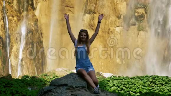 女孩在一个大瀑布前缓慢地挥手视频的预览图
