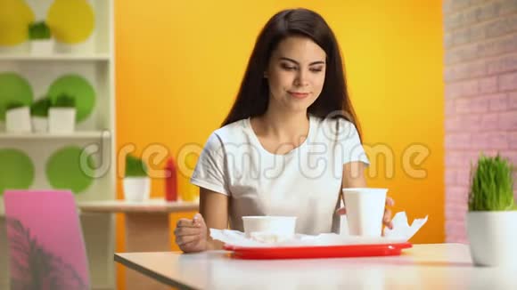 漂亮的女人在食堂里用纸玻璃喝酒吃垃圾食品吃零食视频的预览图