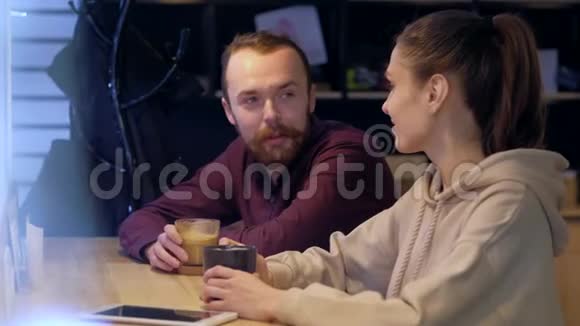 一对夫妇坐在咖啡馆里聊天喝咖啡看智能手机视频的预览图