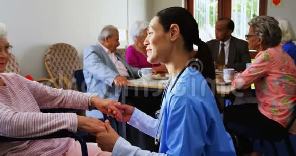 白种人女医生在疗养院安慰悲伤残疾老年妇女的侧视4k视频的预览图
