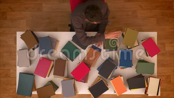 停止运动顶部的镜头男人移动他的手高于消失的书籍在桌子上下载他们的智能手机视频的预览图