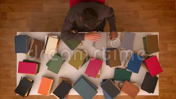 停止移动顶部镜头的人移动他的手在消失的书籍上的桌子下载他们的平板电脑视频的预览图