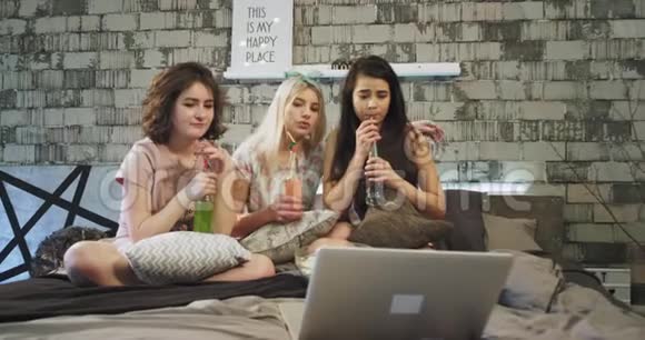 三个最好的朋友女士在一个现代化的卧室阁楼里举行家庭聚会她们看着一部悲伤的电影手里拿着视频的预览图