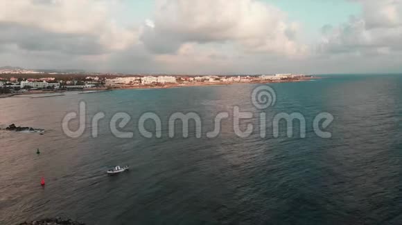 白色的小渔船航行到开阔的海洋蓝天和白色的建筑物在背景上空中无人机射击视频的预览图