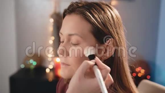 一个化妆师在一个白种人金发模特的脸上涂了一层普通的白色刷子化妆业务视频的预览图