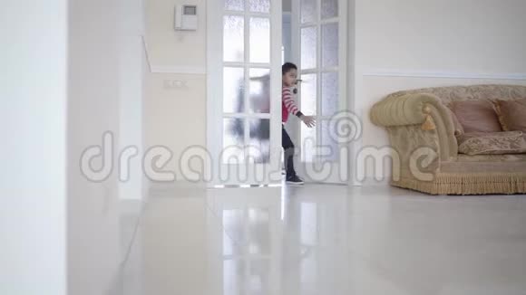 三个快乐的孩子打开门跑到大光房里男孩和两个女孩在房子里玩休闲视频的预览图