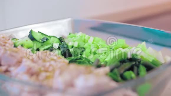 特写慢动作生菜放在一个玻璃沙拉碗里的鸡肉和充满芝麻酱的绿色植物概念视频的预览图