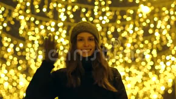 一个幸福的女孩在一条装饰着圣诞灯的街道上的肖像视频的预览图