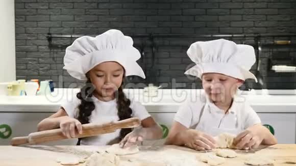穿着厨师帽的可爱孩子在私人房子里做饼干和馅饼背景上的厨具4k视频的预览图