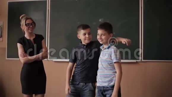 老师在黑板旁帮助男孩年轻女教师学习视频的预览图