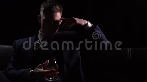 一个穿着三件西装的商人坐在沙发上喝着一杯威士忌视频的预览图