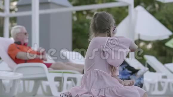成熟的情侣躺在靠近泳池的日光浴床上小可爱的小辫子坐在边上视频的预览图