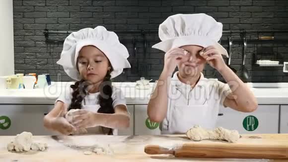 孩子们在私人厨房里一起玩烹饪儿童厨师概念桌子上有面团面粉和擀面杖视频的预览图