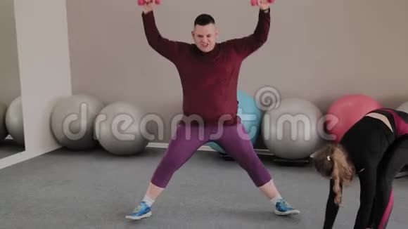 积极超重的女人和健康的男人在地板上做运动有趣的学习视频的预览图