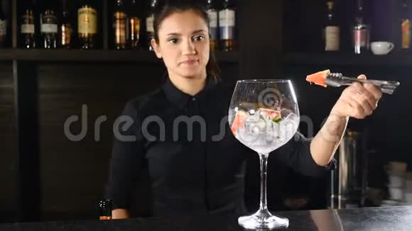 微笑可爱的女酒保把草莓放在一个杯子与碎冰同时准备鸡尾酒夜生活视频的预览图