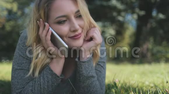 漂亮女孩智能手机对话躺在草坪上视频的预览图
