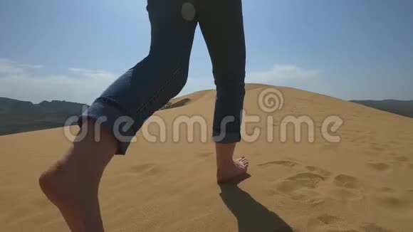 一个女人沿着沙漠里的沙子跑一个女孩赤着脚跑在沙子里的沙丘上视频的预览图