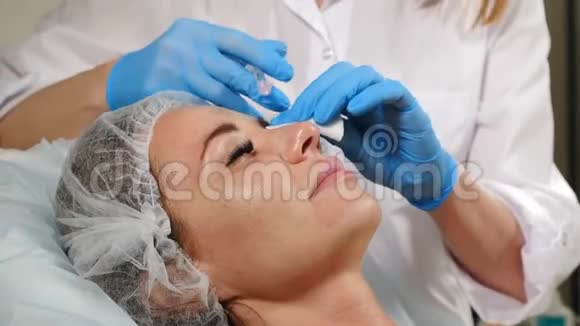 鼻形的非手术矫正在美容过程中的一个年轻女孩把美容师的手举起来视频的预览图