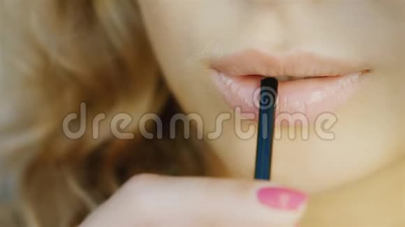一个年轻性感女人的嘴唇在喝着管子里的鸡尾酒微笑着视频的预览图