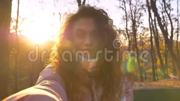 白种人卷发女子在阳光下拍摄秋日公园的自拍照视频的预览图