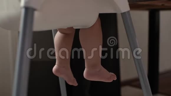 可爱的宝宝坐在高高孩子的椅子上移动他的腿视频的预览图