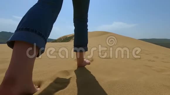一个女人沿着沙漠里的沙子跑一个女孩赤着脚跑在沙子里的沙丘上视频的预览图