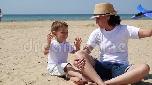 妈妈和宝宝坐在沙滩上女人在飞机上和一个小男孩玩幸福的情绪视频的预览图