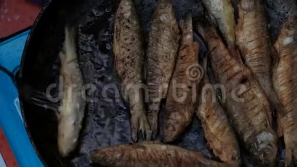 撒上面粉的小鱼用热油在锅里炒雄手用叉子翻鱼做饭视频的预览图