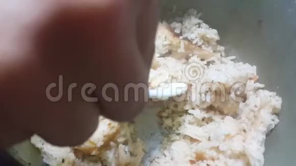 用塑料勺子在炒锅里煮和搅拌米饭视频的预览图