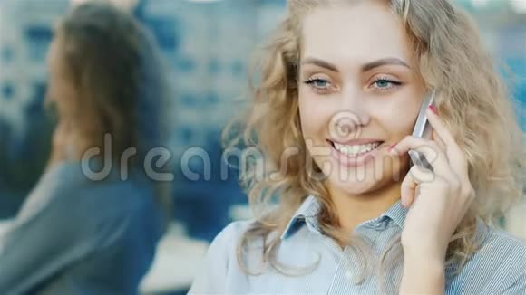 有魅力的女人在电话里说话的肖像微笑着风吹进她的头发视频的预览图