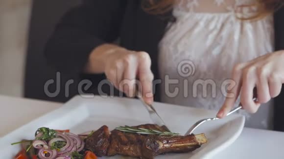 在餐馆里用刀叉吃烤牛排的女人的手的特写视频的预览图