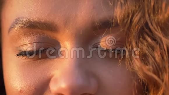 在秋日公园背景下白种人卷发女子微笑着观看镜头的特写眼画像视频的预览图