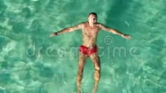 在蓝色海水中漂浮的雄性游泳者上面的无人机绿海视频的预览图