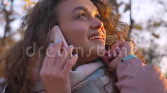 秋日公园里白种人卷发女士坐在长凳上愉快地用手机聊天她的特写照片视频的预览图