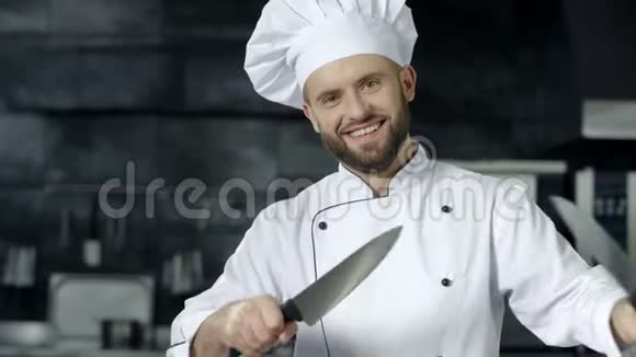 男厨师在厨房拿刀玩得很开心微笑厨师磨划过的刀视频的预览图