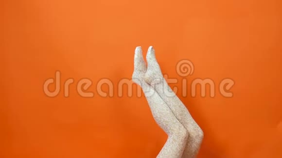 白鱼网丝袜完美的女人腿在明亮的橙色背景工作室视频的预览图