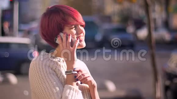在模糊的街道背景下幸福的漂亮粉红头发女孩在手机上说话的肖像视频的预览图
