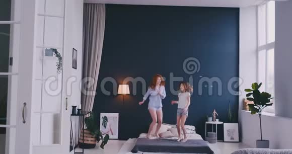 快乐的母亲和她的女儿在儿童房跳上床视频的预览图