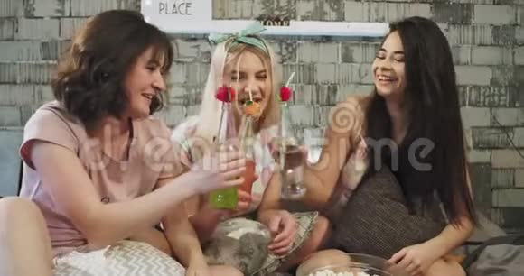 在现代化的阁楼卧室里多民族的少女们可以在一个过夜的夜晚喝一些五颜六色的饮料视频的预览图