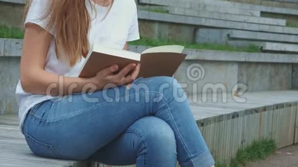 公园里年轻漂亮的女孩正在看书一个学生正在学习一本书翻页混凝土上的裂缝视频的预览图