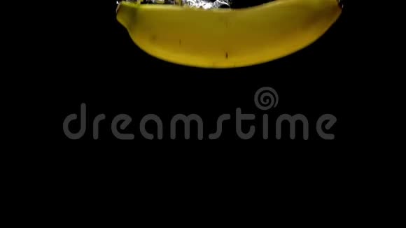 黄色香蕉在黑色背景下落入透明水视频的预览图
