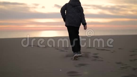 那个男孩在日落时沿着海滩跑步视频的预览图