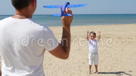 幸福家庭父子在海边玩耍一个人发射一架玩具飞机旅游和户外娱乐活动视频的预览图