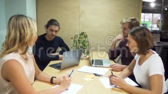 四位年轻企业家在办公室会议室讨论使用笔记本电脑的新创业战略视频的预览图