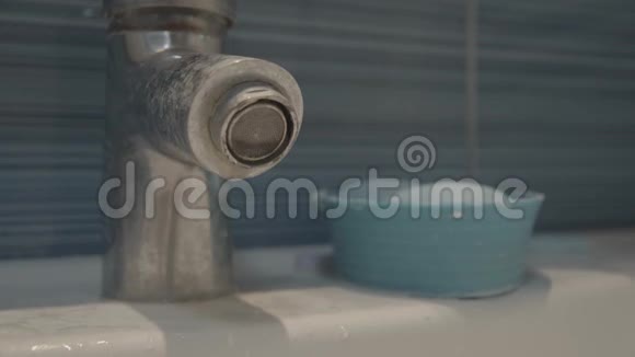钙化和肮脏的浴室水槽与自来水自来水一滴滴与背景中的蓝色瓷砖隔离视频的预览图