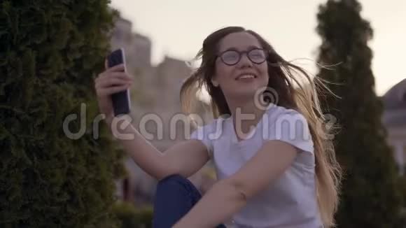你好年轻女孩正对着屏幕对着她的男朋友在春天公园打视频电话时正对着镜头挥手视频的预览图