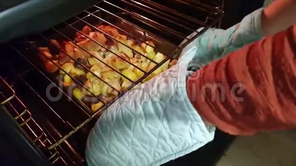 家庭主妇从烤箱里拿出土豆和肉作为晚餐视频的预览图