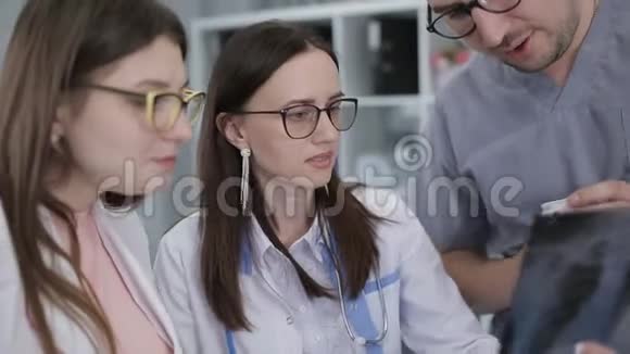 在工作人员房的x光图像附近的医生的护理医生喝茶用肋骨看X光视频的预览图