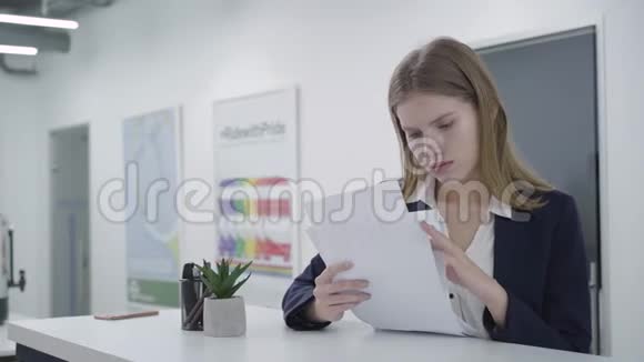 关心体贴的年轻女士穿着正式服装站在柜台前仔细检查办公室的文件视频的预览图