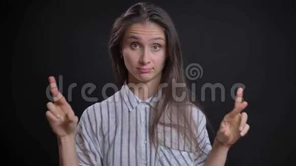 美丽的白种人长发女人的肖像画用交叉的手指在黑色上表示对好运的希望视频的预览图